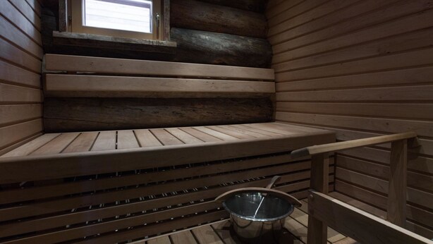 A sauna with wooden benches, a window, and a metal basin.