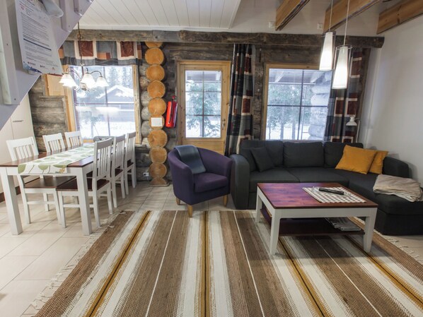 A cozy living room with a sofa, a coffee table, and a dining area with chairs and a table.