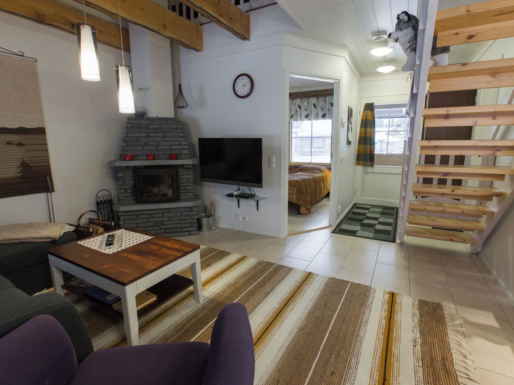 Ein Wohnzimmer mit Kamin, Fernseher, Sofa und einer Treppe.