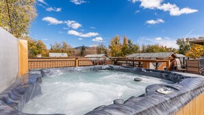 Un jacuzzi con cubierta de madera y vista a una zona residencial con casas y árboles.