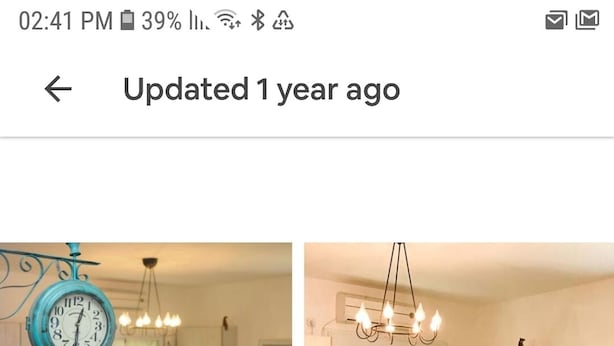 A kitchen with a central island, a hanging light fixture, and a wall-mounted clock.
