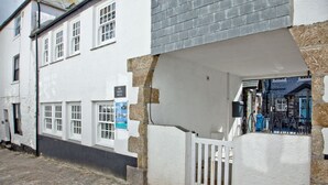 A white building with a stone facade, a covered porch, and a sign reading "Iris Juliet Wella". - The Garth 5* Gold Award Luxury Property (St Ives)