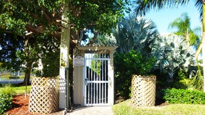 Una entrada protegida por una verja a una propiedad privada, con un cartel que indica 'Marco Beach Vacation Suites, Black Club of Marco PRIVADO'.