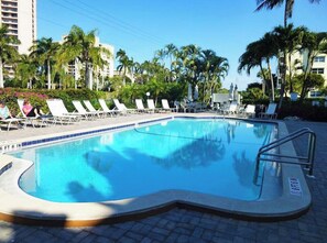 Una piscina con sillas de descanso y palmeras.