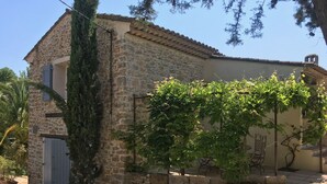 A stone building with a tiled roof, a door, and a small balcony.