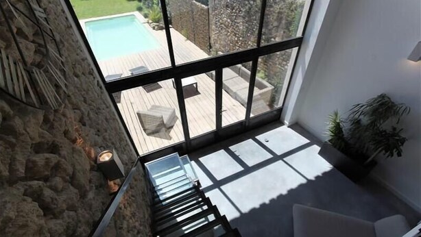 Un intérieur moderne avec un escalier menant à un balcon donnant sur une piscine.
