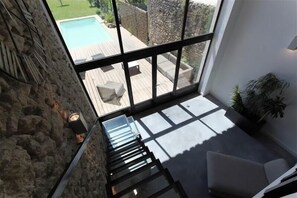 A modern interior with a staircase leading to a balcony overlooking a swimming pool. - Renovated Provençal farmhouse in a quiet environment, with pool (Sainte-Cécile-les-Vignes)