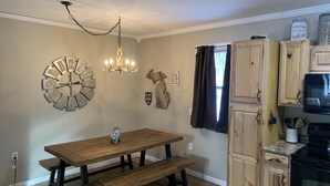 Una cocina con armarios de madera, un microondas negro y una mesa de madera con bancos.