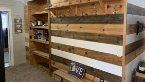 Una pared de madera rústica con estantes, ganchos y un banco.