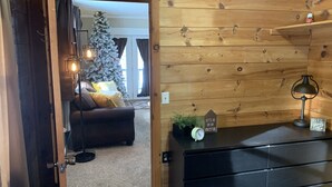 Una habitación acogedora con detalles de madera, un aparador negro, una planta pequeña y un cartel que dice 'Let's go on an adventure'.