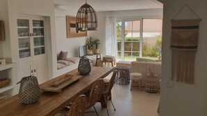 Uma cozinha espaçosa com mesa de madeira, cadeiras de vime e um espaço de refeições com sofá e cadeiras.