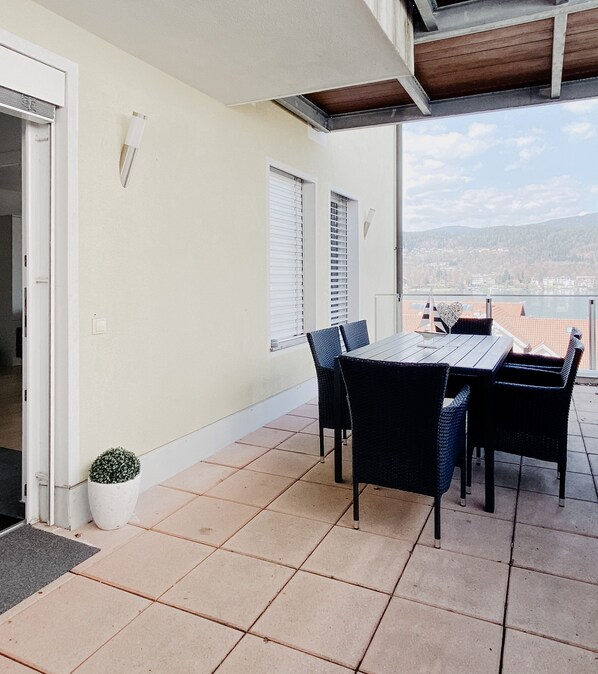 Une terrasse avec une table et des chaises, un pot de fleurs et une vue sur le paysage urbain.