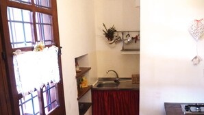 Una cocina compacta con ventana, radiador, lavamanos y estufa.
