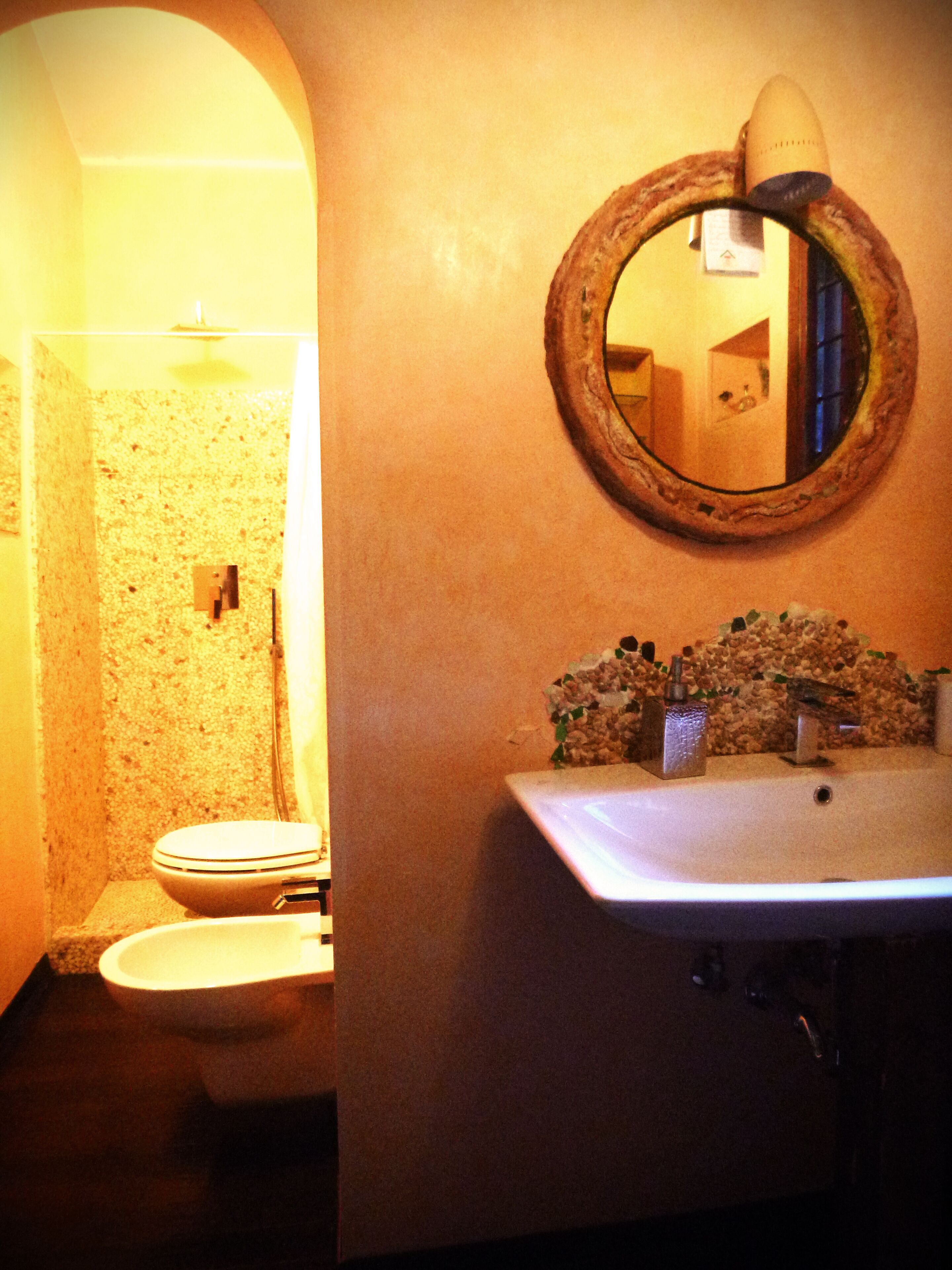Een badkamer met toilet, wastafel en spiegel.