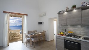 Una cocina moderna con vistas al mar, un comedor con sillas de madera y un balcón con vistas.