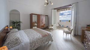 Un dormitorio amplio con una cama grande, un armario, una silla y vistas al mar.