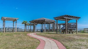 Un parque con quioscos de madera, un sendero curvo y edificios al fondo.