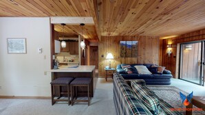 L’intérieur d’un chalet accueillant, avec un coin repas, un canapé et une grande fenêtre.