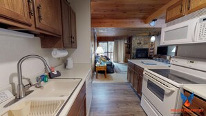 Une cuisine avec des meubles de rangement en bois, un évier, une cuisinière et un four à micro-ondes.