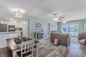 Enjoy ocean views from the sofa in this spacious living area, featuring a dining table, kitchen, and ceiling fan.