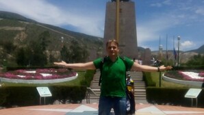 En person står foran et monument med en plade, der viser teksten "ECUADOR 0-0-0 LAT".