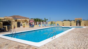 Una piscina con cubierta de baldosas, sillas de descanso y plantas en macetas.