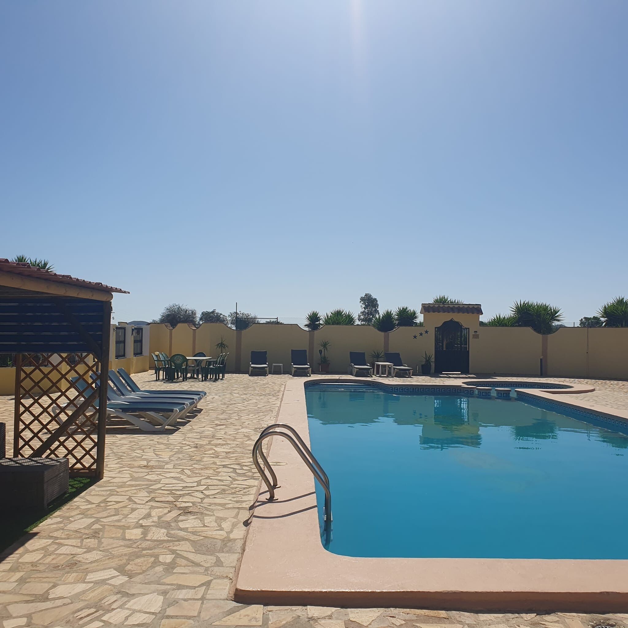Une piscine dotée de chaises longues et d’un espace de détente abrité.