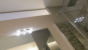 A modern interior with a glass railing, recessed lighting, and a checkered floor pattern.