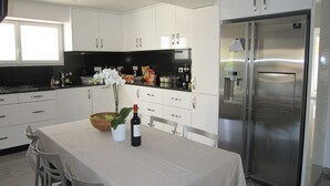Una cucina moderna con mobili bianchi, un frigorifero in acciaio inox e un'area pranzo con un tavolo apparecchiato per due.