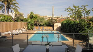 Area piscina sul tetto con poltrona relax, tavolo da pranzo e piccolo giardino.