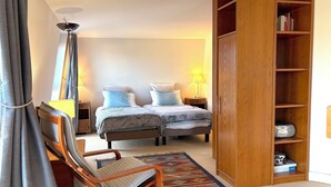 A bedroom with a bed, a chair, a bookshelf, and a lamp. - Le Penthouse Thorigny (Paris)