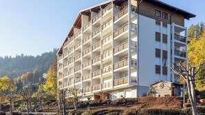 A multi-story hotel with balconies, a flat roof, and a hillside location.