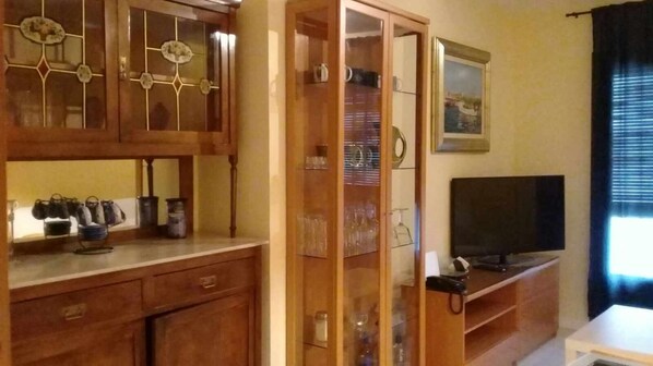 Une pièce avec des meubles de rangement en bois, un téléviseur et une vitrine.