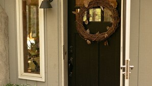 Eine Haustür mit Adventskranz, Topfpflanze und Fenster mit Lampe.