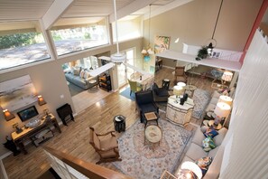 A spacious living area with a high ceiling, large windows, and a view of the outdoors.