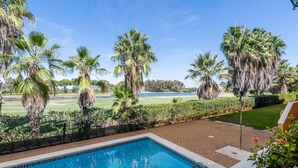 A swimming pool with a view of a golf course and palm trees. - La Quinta de Isla Canela II - Isla Canela Golf GQHII2P2 (Isla Canela)