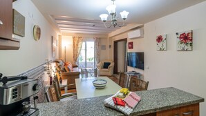A modern kitchen with a dining area, a coffee machine, and a TV. - La Quinta de Isla Canela II - Isla Canela Golf GQHII2P2 (Isla Canela)
