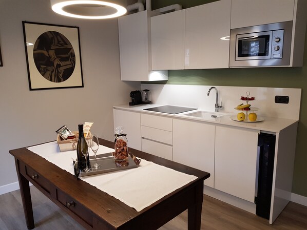 A modern kitchen with white cabinetry, a stainless steel microwave, a sink, and a dining table with a placemat.