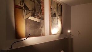 A hotel room with a bed, two paintings on the wall, and a bedside lamp. - Chocolat la Mairie in Omegna (Omegna)