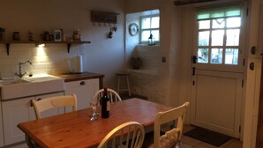 Une cuisine avec une table en bois, des chaises, un évier et une fenêtre.