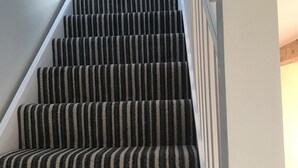 A staircase with striped carpet and white railings. - Tigh a Chabar, Savary. Nr Lochaline.  Cosy cottage, sleeps 4.  Sea views. (Morvern, Argyll)