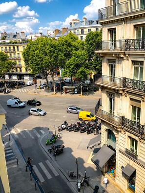 A street view with parked cars, motorcycles, and a yellow van.