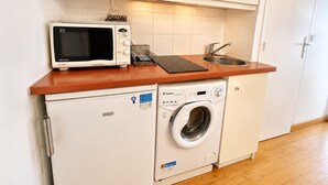 Eine kompakte Küchenzeile mit Mikrowelle, Toaster, Spüle und Waschmaschine.