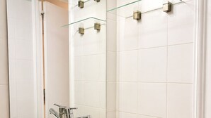 Ein Badezimmer mit einem weißen Waschbecken, einem Spiegel und einer Holzauslage.