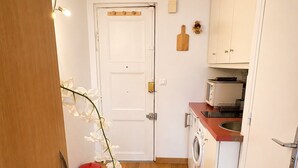 Une cuisine compacte équipée d’un lave-linge, d’un four à micro-ondes et d’un évier.