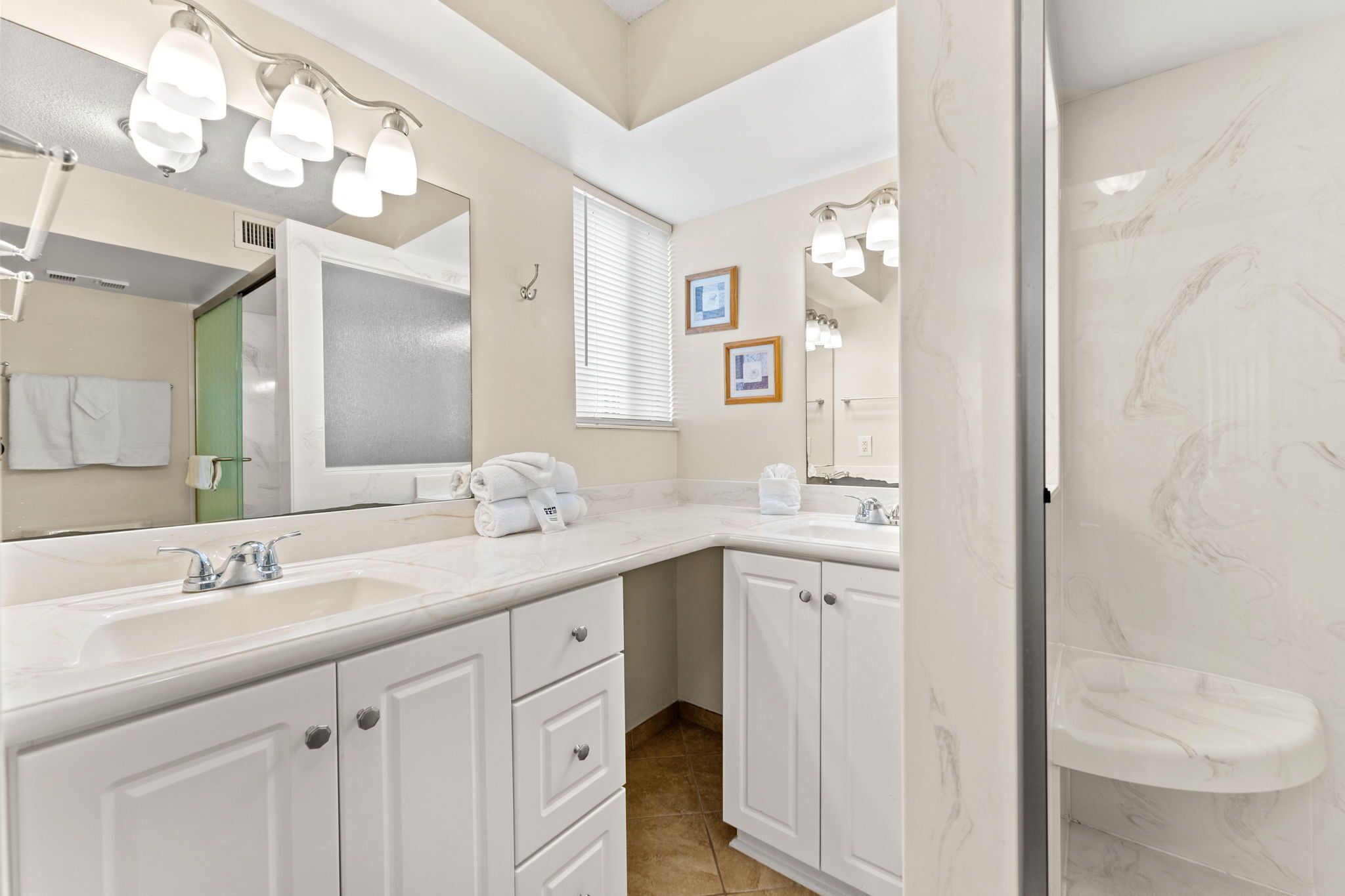 Une salle de bain avec deux lavabos, un grand miroir et un meuble-lavabo avec des tiroirs.