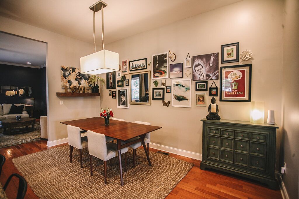 A dining area with a wooden table and chairs, surrounded by framed pictures on the walls.