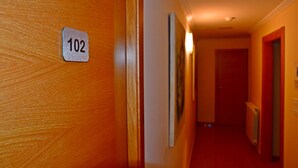 A hallway with a wooden door and a sign indicating room number 102. - Hotel Reigosa (Ponte Caldelas)