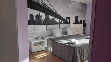 Un dormitorio con cama, mesitas de noche y un mural con vista a la ciudad.