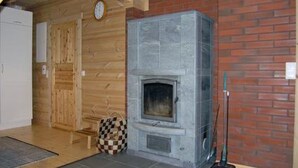 Una habitación con chimenea, paredes de madera, un tapete de cuadros y un reloj en la pared.